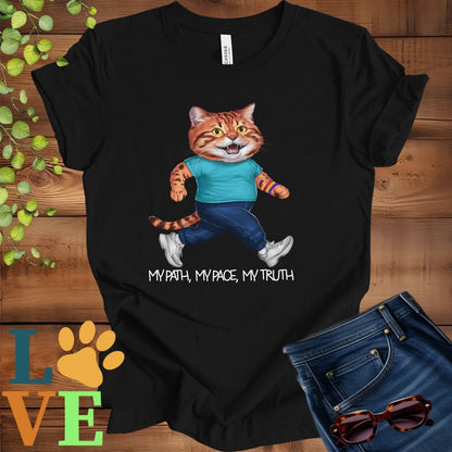 Black t-shirt featuring an anthropomorphic Bengal cat in exercise wear walking confidently with the slogan, "My path, my pace, my truth."