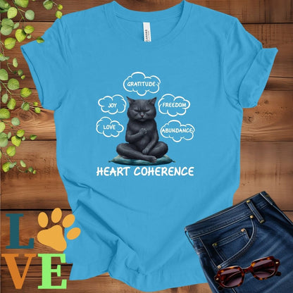 Bright aqua blue t-shirt with a meditating black cat, surrounded by floating emotion bubbles labelled love, joy, gratitude, freedom, abundance, and 'Heart Coherence' slogan.
