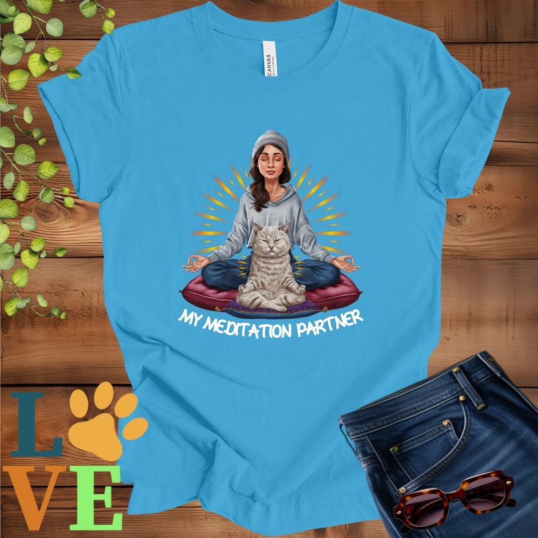Bright aqua blue t-shirt featuring a woman meditating with her British Shorthair cat and the slogan "My meditation partner".