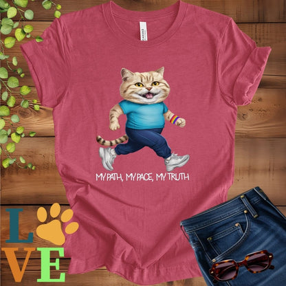 Muted raspberry pink (heather raspberry) t-shirt featuring an anthropomorphic British Shorthair cat in exercise wear walking confidently with the slogan, "My path, my pace, my truth."