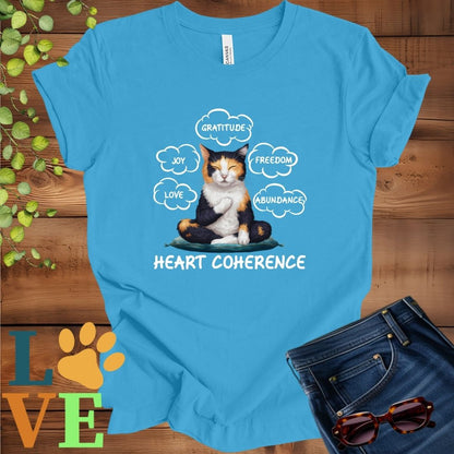 Bright aqua blue t-shirt with a meditating calico cat, surrounded by floating emotion bubbles labelled love, joy, gratitude, freedom, abundance, and 'Heart Coherence' slogan.