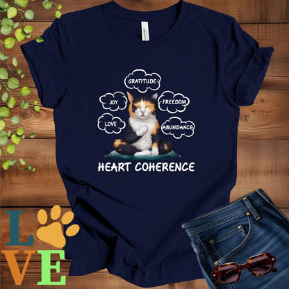 Navy blue t-shirt with a meditating calico cat, surrounded by floating emotion bubbles labelled love, joy, gratitude, freedom, abundance, and 'Heart Coherence' slogan.