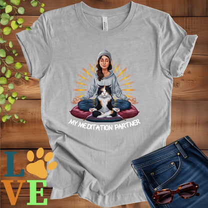 Light grey heather (athletic heather) t-shirt featuring a woman meditating with her calico cat and the slogan "My meditation partner".