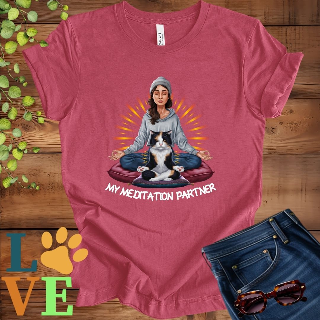 Muted raspberry pink (heather raspberry) t-shirt featuring a woman meditating with her calico cat and the slogan "My meditation partner".