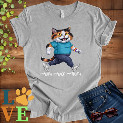 Light grey heather (athletic heather) t-shirt featuring an anthropomorphic calico cat in exercise wear walking confidently with the slogan, "My path, my pace, my truth."
