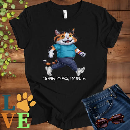 Black t-shirt featuring an anthropomorphic calico cat in exercise wear walking confidently with the slogan, "My path, my pace, my truth."



