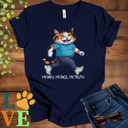 Navy blue t-shirt featuring an anthropomorphic calico cat in exercise wear walking confidently with the slogan, "My path, my pace, my truth."


