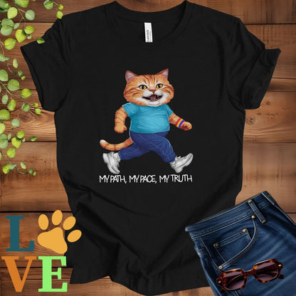 Black t-shirt featuring an anthropomorphic ginger cat in exercise wear walking confidently with the slogan, "My path, my pace, my truth."
