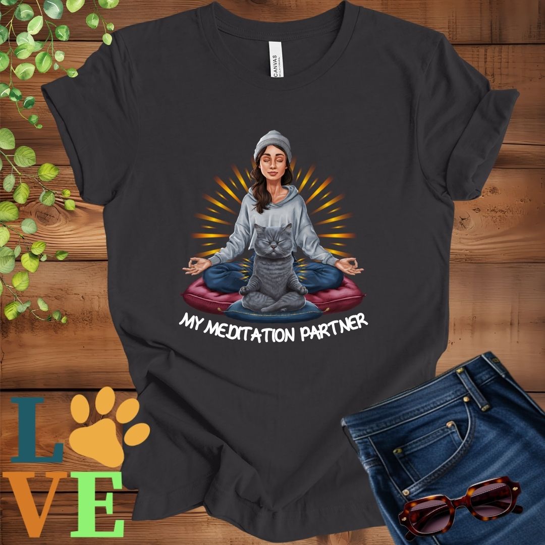 Dark grey heather t-shirt featuring a woman meditating with her gray British Shorthair cat and the slogan "My meditation partner".