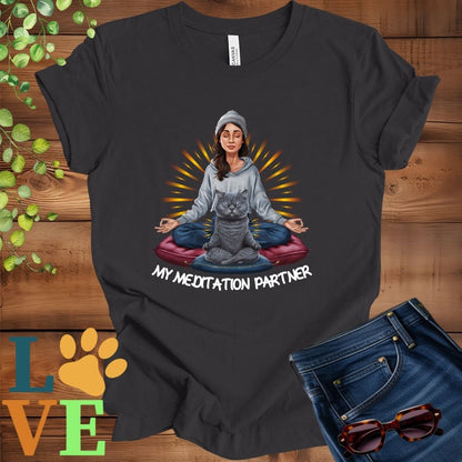 Dark grey heather t-shirt featuring a woman meditating with her gray British Shorthair cat and the slogan "My meditation partner".
