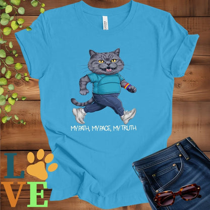 Bright aqua blue t-shirt featuring an anthropomorphic gray British Shorthair cat in exercise wear walking confidently with the slogan, "My path, my pace, my truth."