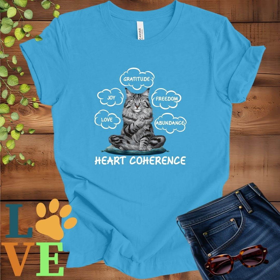 Bright aqua blue t-shirt with a meditating Maine Coon cat, surrounded by floating emotion bubbles labelled love, joy, gratitude, freedom, abundance, and 'Heart Coherence' slogan.
