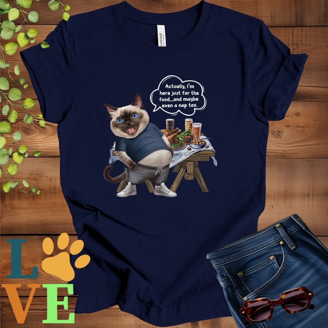 Navy blue t-shirt with an anthropomorphic Siamese cat, standing in front of a table with food and drinks, showing its pot belly and humorous speech bubble message.