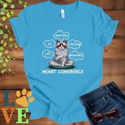 Bright aqua blue t-shirt with a meditating Ragdoll cat, surrounded by floating emotion bubbles labelled love, joy, gratitude, freedom, abundance, and 'Heart Coherence' slogan.
