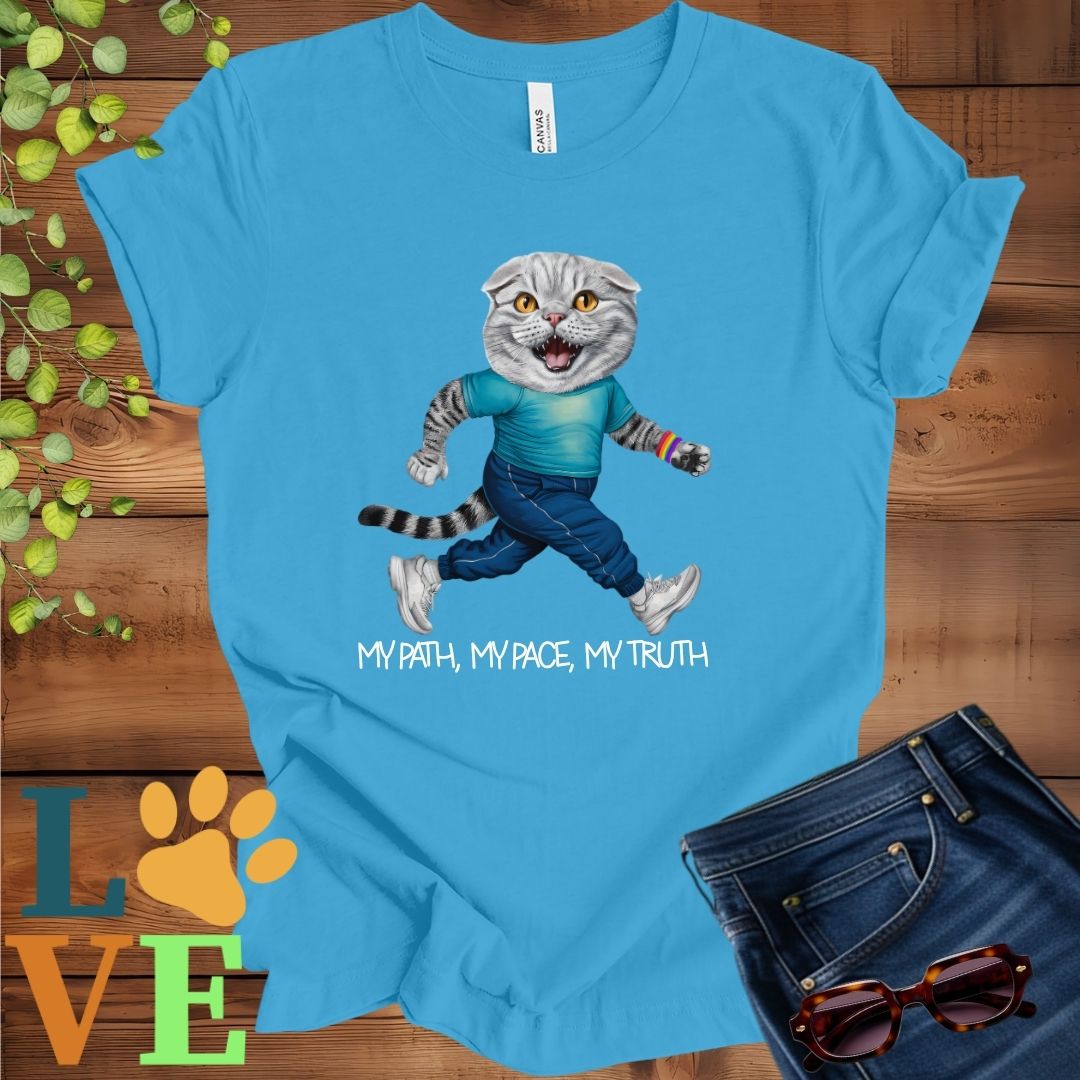 Bright aqua blue t-shirt featuring an anthropomorphic Scottish Fold cat in exercise wear walking confidently with the slogan, "My path, my pace, my truth."
