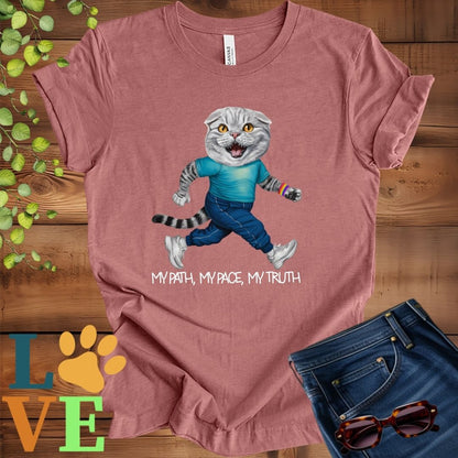 Muted mauve-purple (heather mauve) t-shirt featuring an anthropomorphic Scottish Fold cat in exercise wear walking confidently with the slogan, "My path, my pace, my truth."