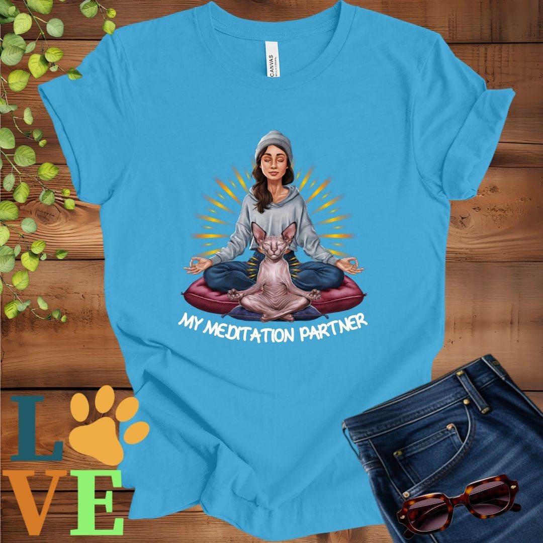 Bright aqua blue t-shirt featuring a woman meditating with her Sphynx cat and the slogan "My meditation partner".
