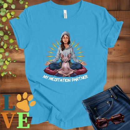 Bright aqua blue t-shirt featuring a woman meditating with her Sphynx cat and the slogan "My meditation partner".
