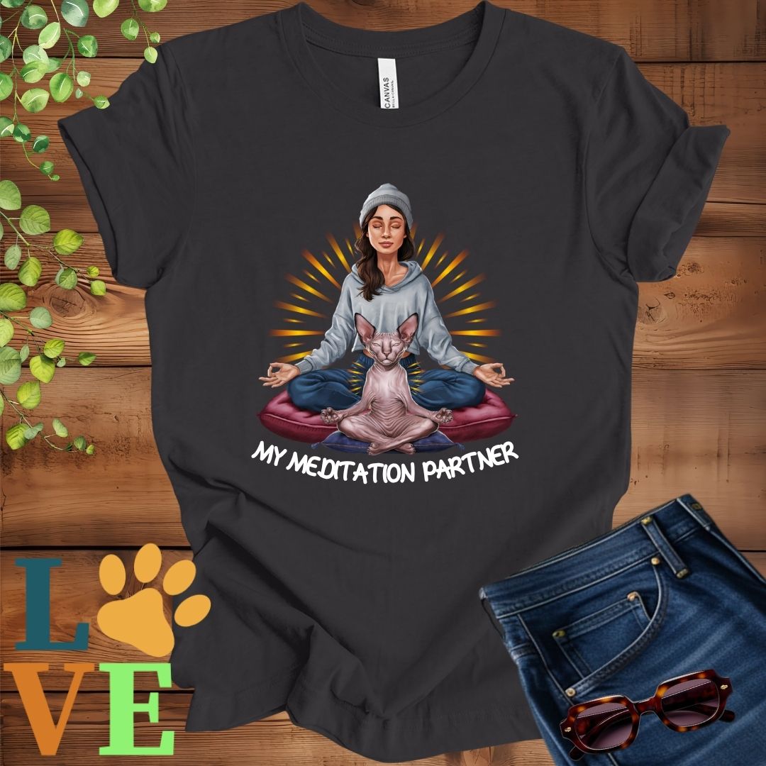 Dark grey heather t-shirt featuring a woman meditating with her Sphynx cat and the slogan "My meditation partner".
