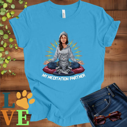 Bright aqua blue t-shirt featuring a woman meditating with her tabby cat and the slogan "My meditation partner".