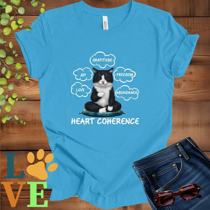 Bright aqua blue t-shirt with a meditating tuxedo cat, surrounded by floating emotion bubbles labelled love, joy, gratitude, freedom, abundance, and 'Heart Coherence' slogan.