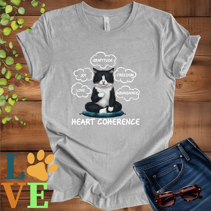 Light grey heather (athletic heather) t-shirt with a meditating tuxedo cat, surrounded by floating emotion bubbles labelled love, joy, gratitude, freedom, abundance, and 'Heart Coherence' slogan.