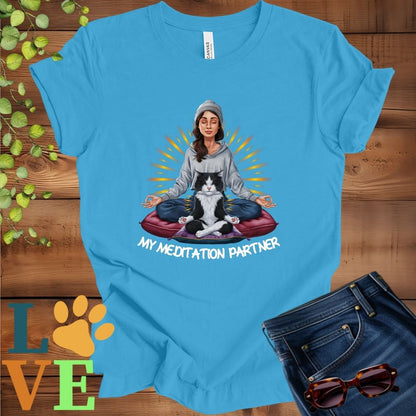 Bright aqua blue t-shirt featuring a woman meditating with her tuxedo cat and the slogan "My meditation partner".